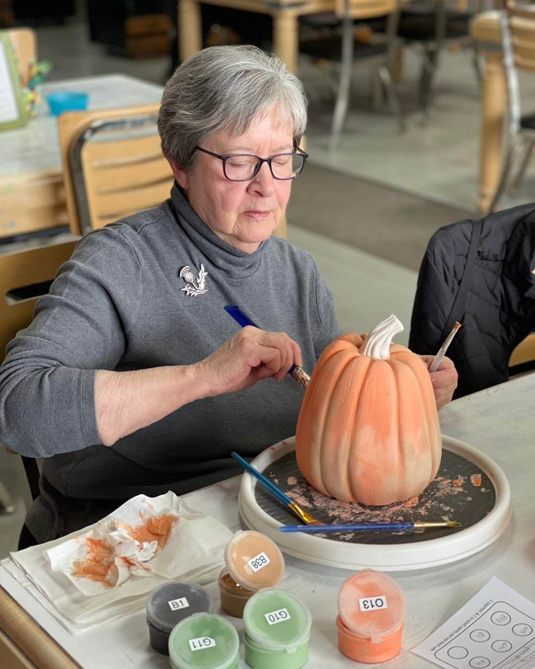 senior woman painting a ceramic pumpkin