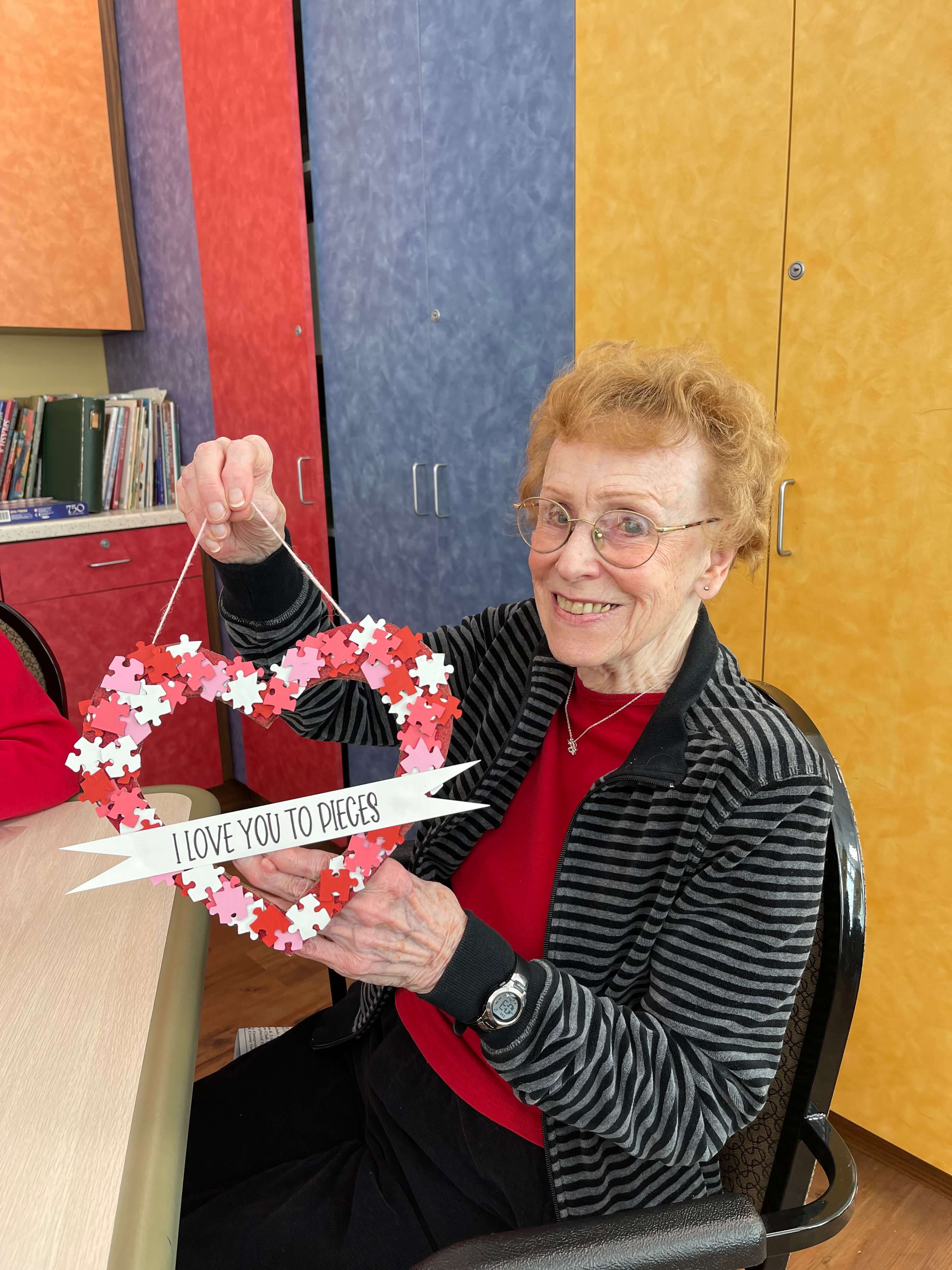 senior woman holding up a valentine's day decoration