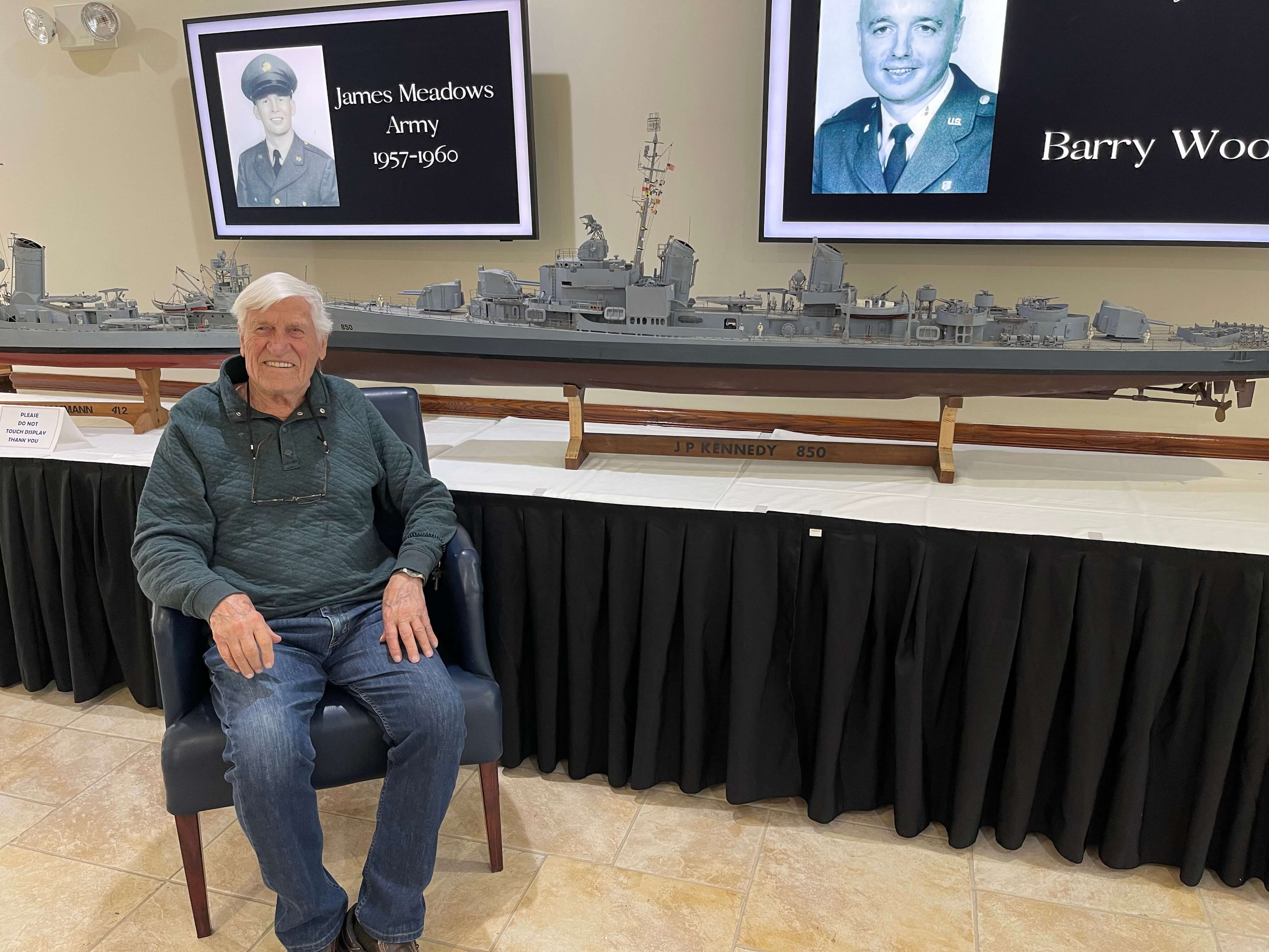 senior man posing in front of a boat replica